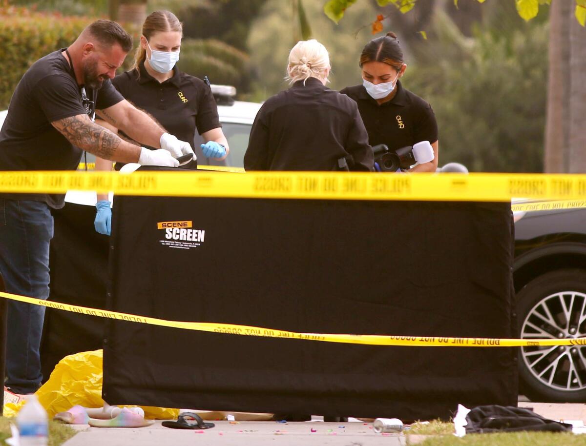 Law enforcement investigate the scene of a stabbing, resulting in the death of two people,  in Huntington Beach.