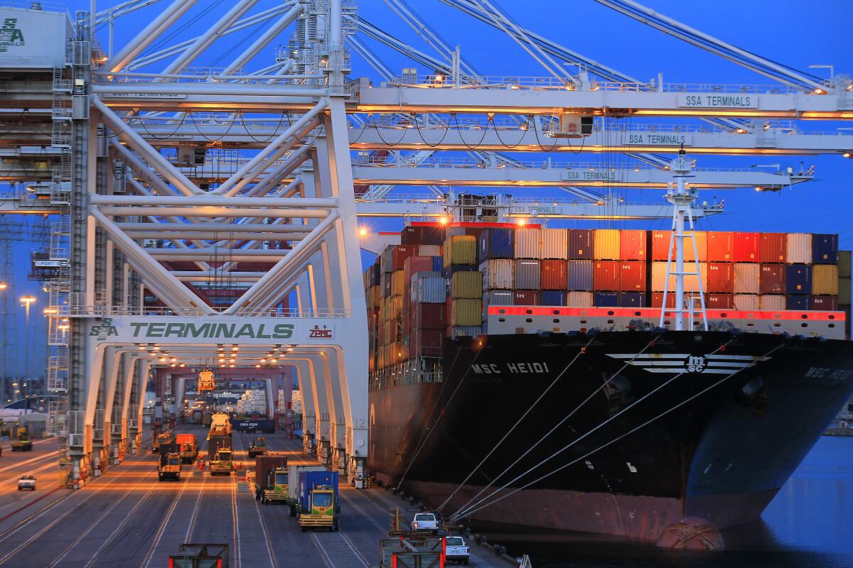 Cranes take cargo containers from a ship docked in the Port of Los Angeles in April.