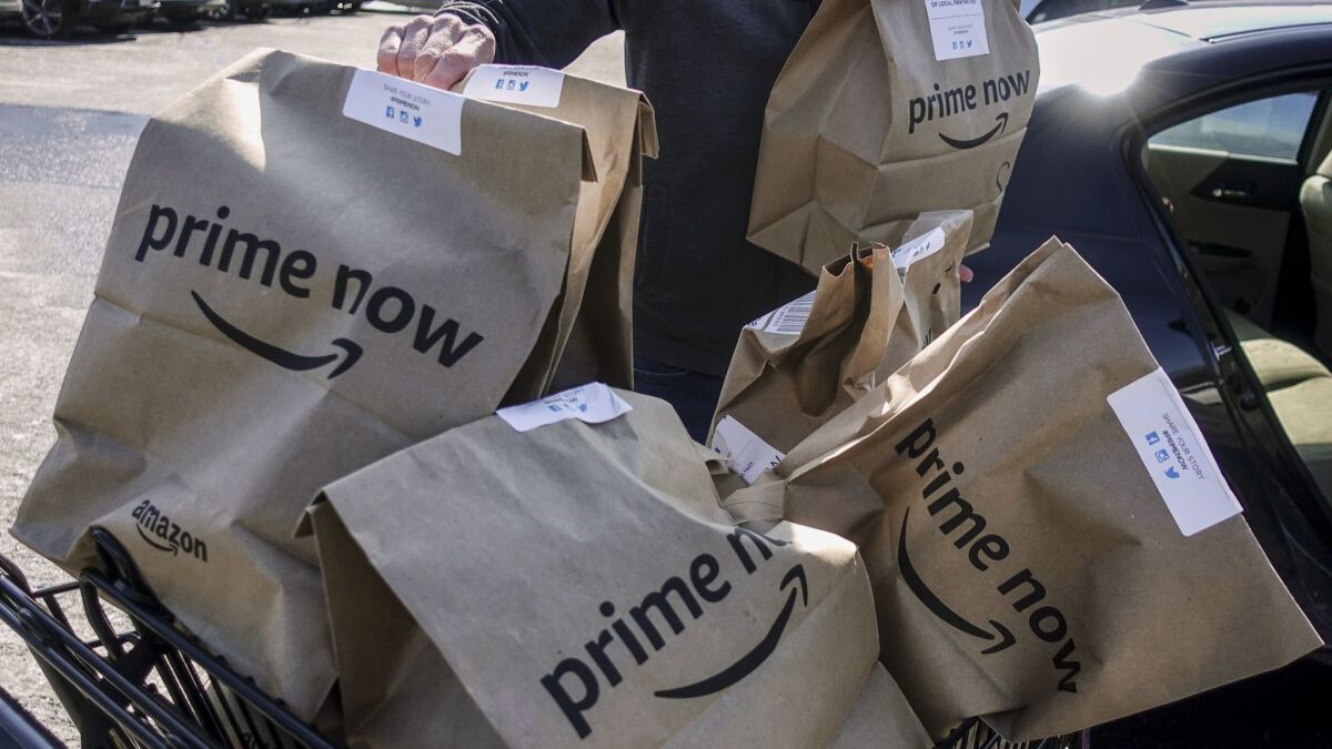 Amazon Prime Now bags full of groceries are loaded for delivery outside a Whole Foods store.