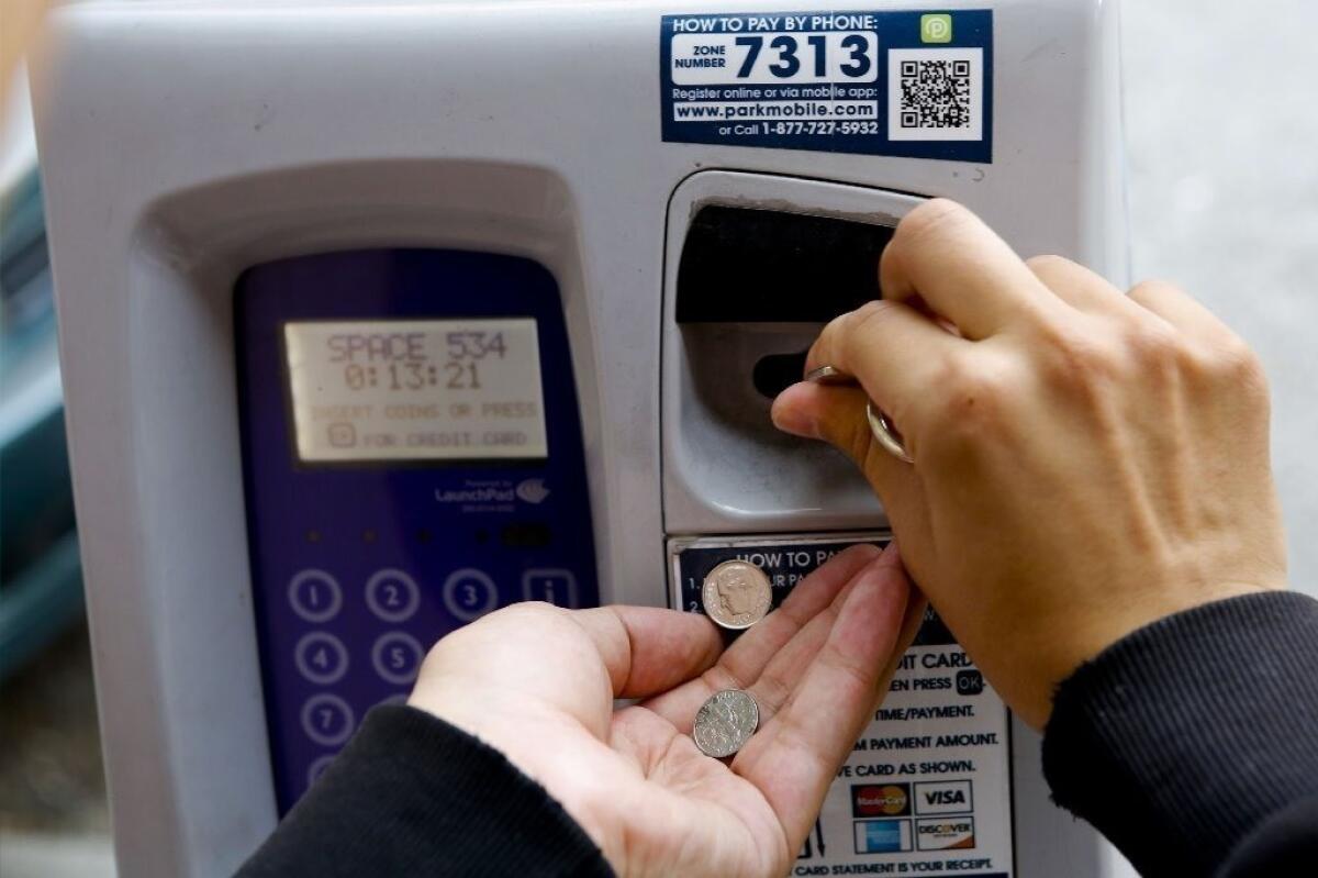 A Westwood man feeds one of the newfangled L.A. city parking meters, this one in downtown Los Angeles. The meter also takes credit cards.