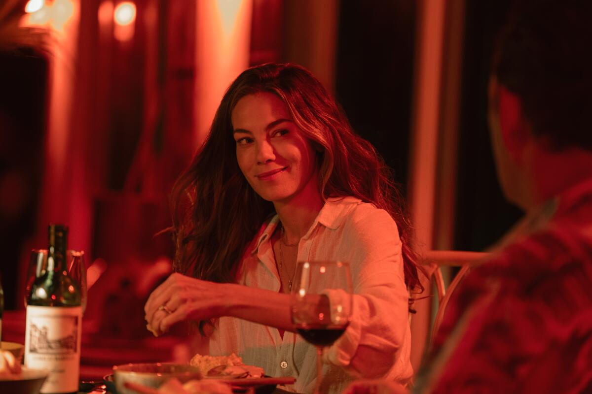 A smiling woman at a dining table.