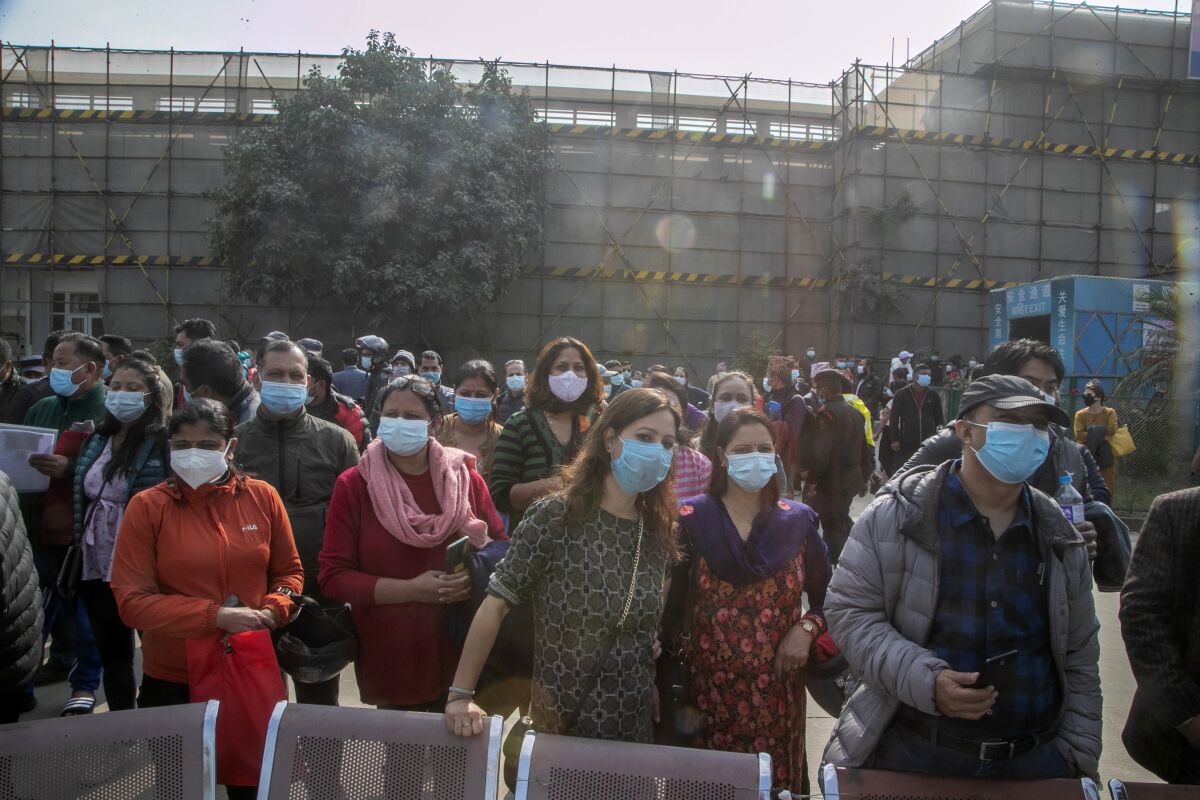 FILE- Adults wait for children receiving the Pfizer-BioNTech vaccine for COVID-19 in Kathmandu, Nepal, Tuesday, Nov. 23, 2021. Nepalese authorities on Monday reported the first cases of the omicron variant in the Himalayan nation. (AP Photo/Niranjan Shrestha, File)