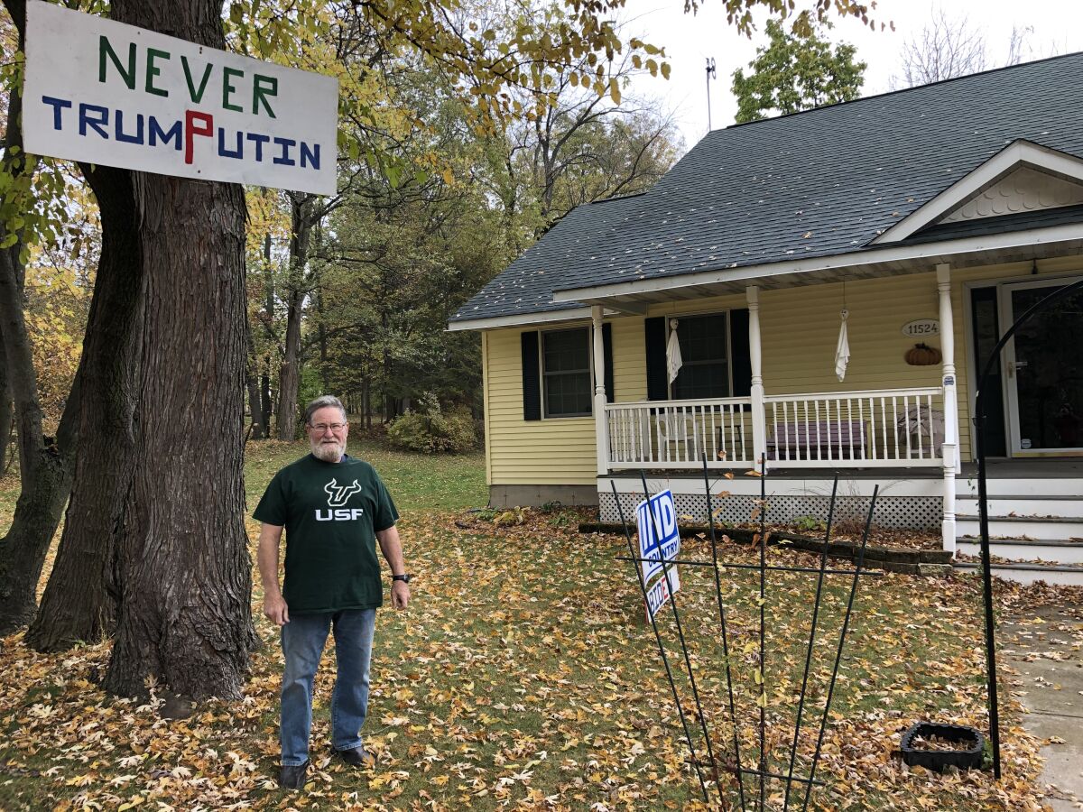 Phillip Bunton with a "Never TrumPutin" sign he bolted to a tree in front of his house in Trempealeau, Wisconsin
