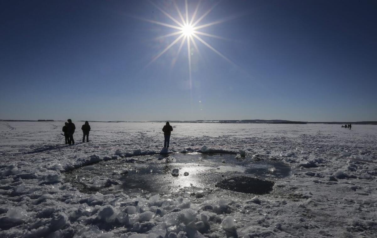 Russian people stand near a giant hole in frozen Lake Chebarkul that was reportedly made by a meteorite from the Chelyabinsk fireball in February.
