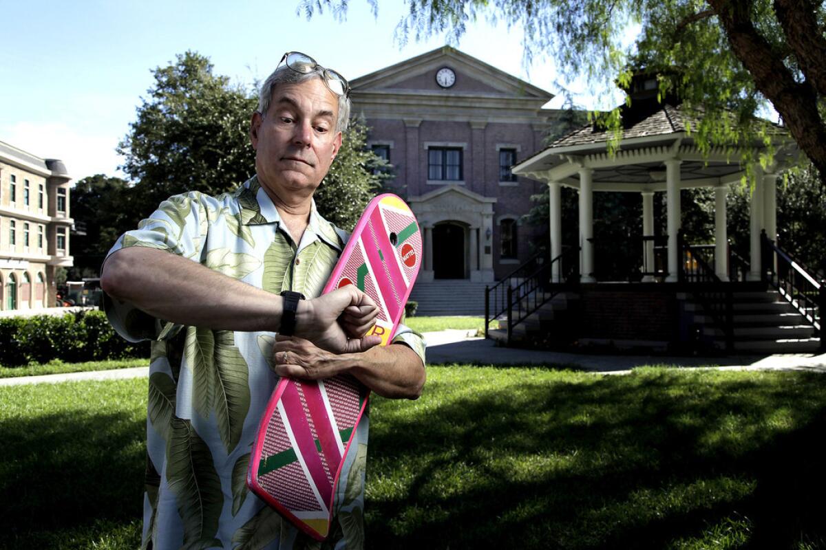 Bob Gale, writer and producer of "Back to the Future," stands in front of the movie's famous clock tower with the official prop hoverboard from the film.