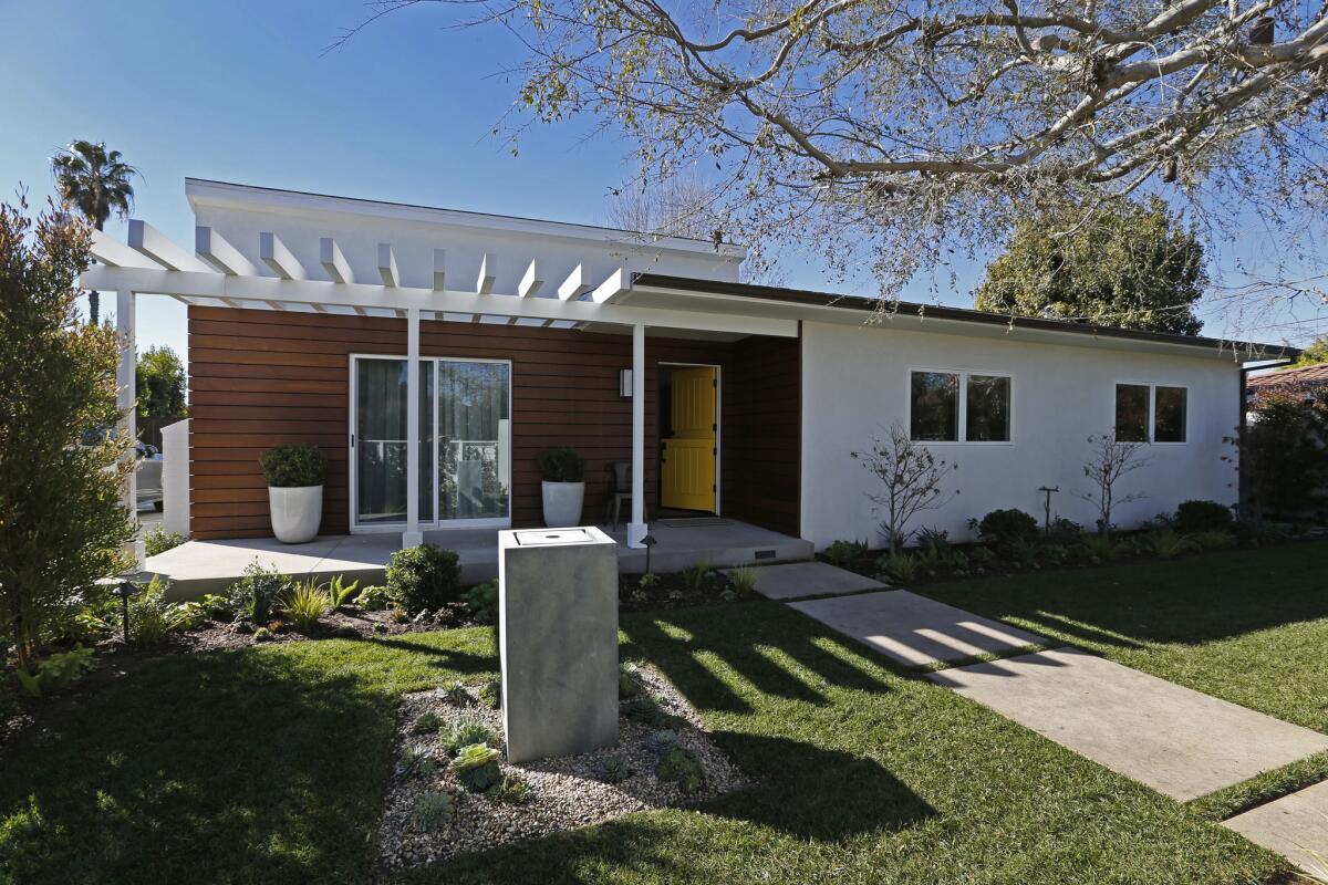 The exterior of the 1950 house offers a modern Ranch update with a mix of white stucco, weathered ipe panels and board form concrete. Heitler added a trellis in the front and back to add a sense of what he calls "solid geometry."