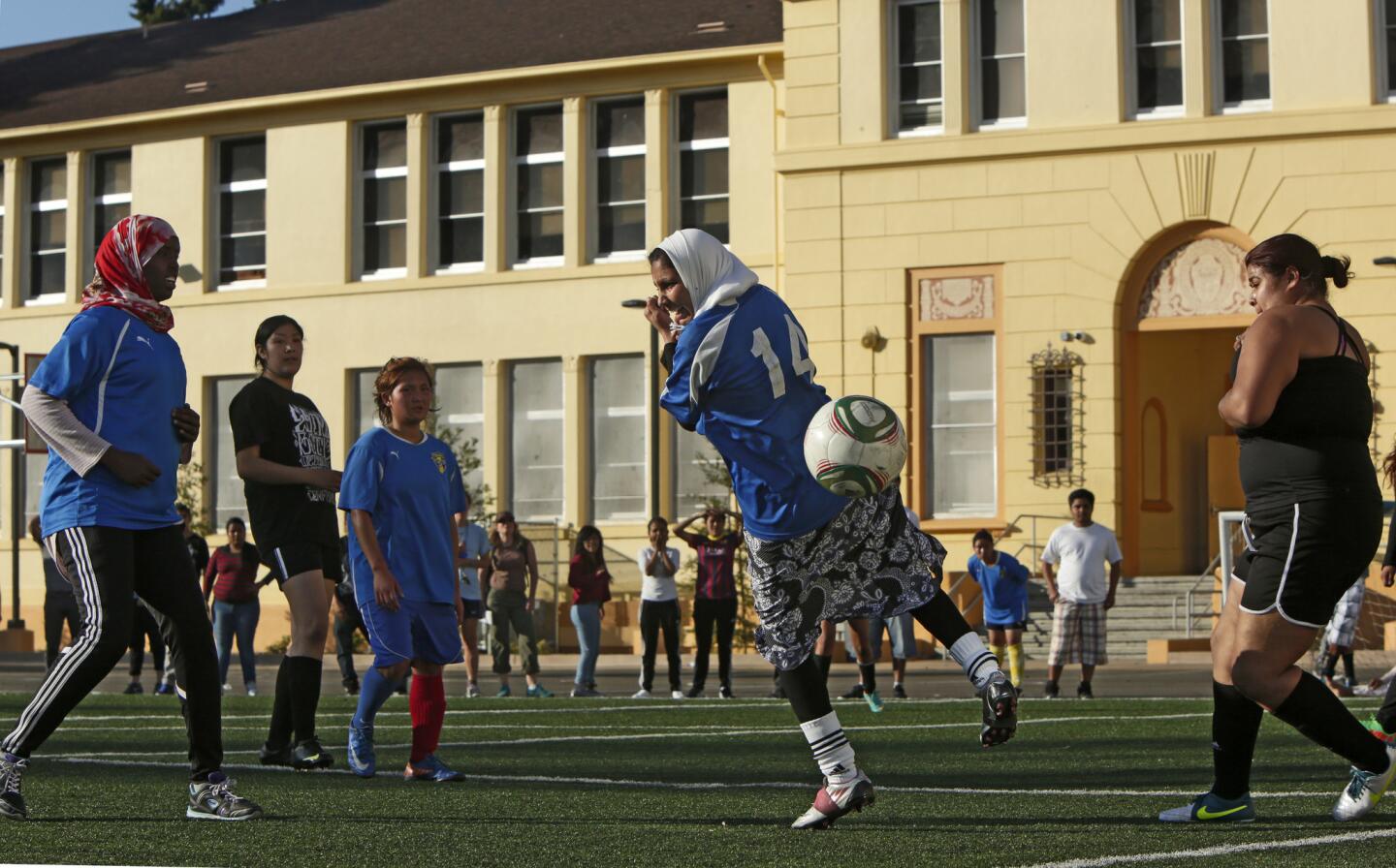 Somali student Fatuma Hussein, left, in red scarf, watches as Afghani student Marium Sarwari misses a header in their soccer match against MetWest High School in Oakland.
