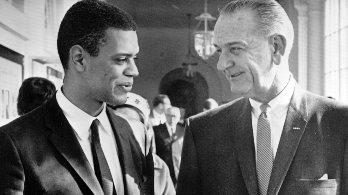 President Lyndon B. Johnson, right, chats with Roger Wilkins, his director of the federal Community Relations Service, in 1966.