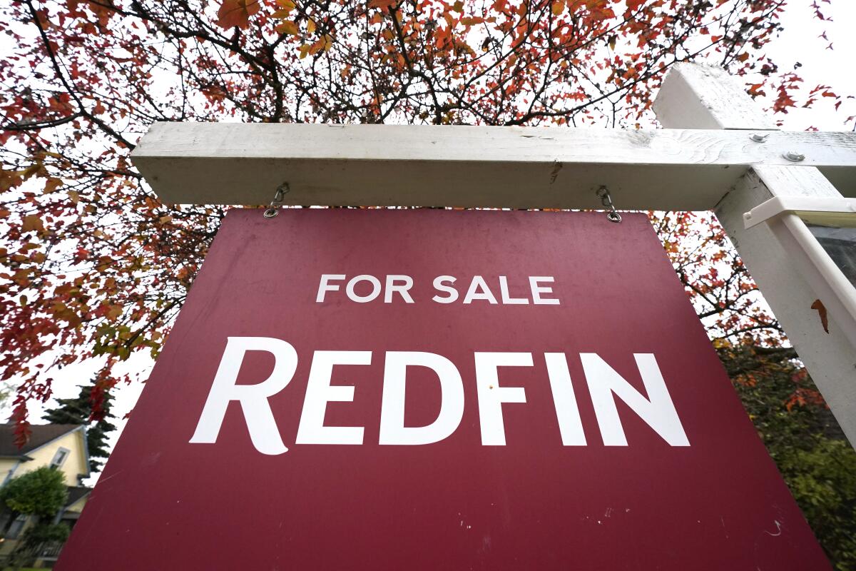 A Redfin "for sale" sign stands in front of a house