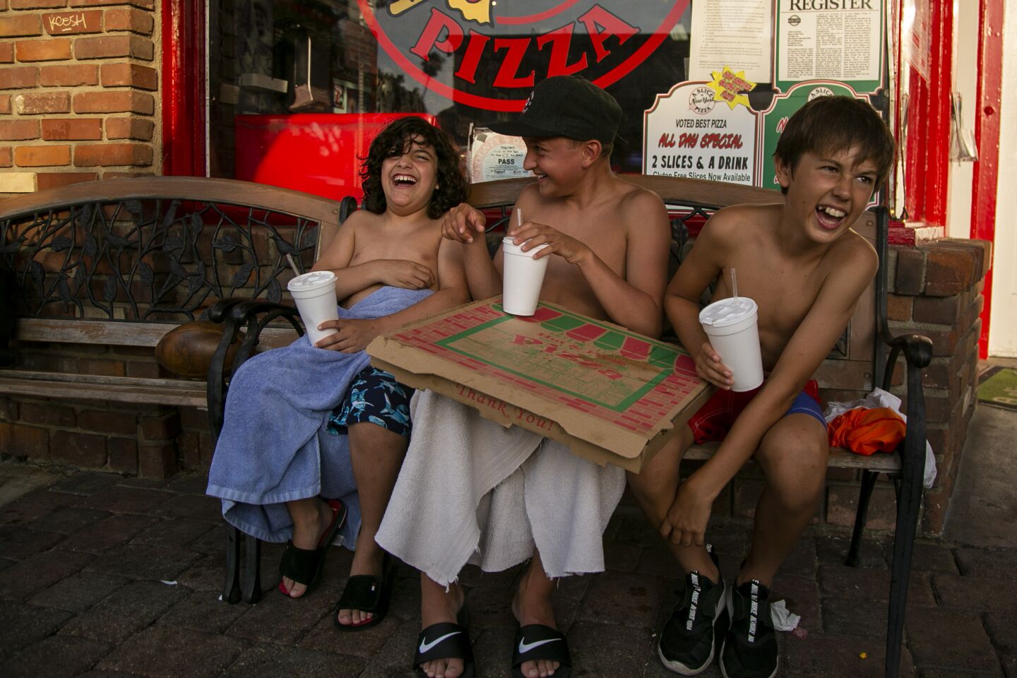 Sebastian Grand, 11, Leo Grand, 13, Constantin Condraschi, 12, with pizza in Seal Beach.