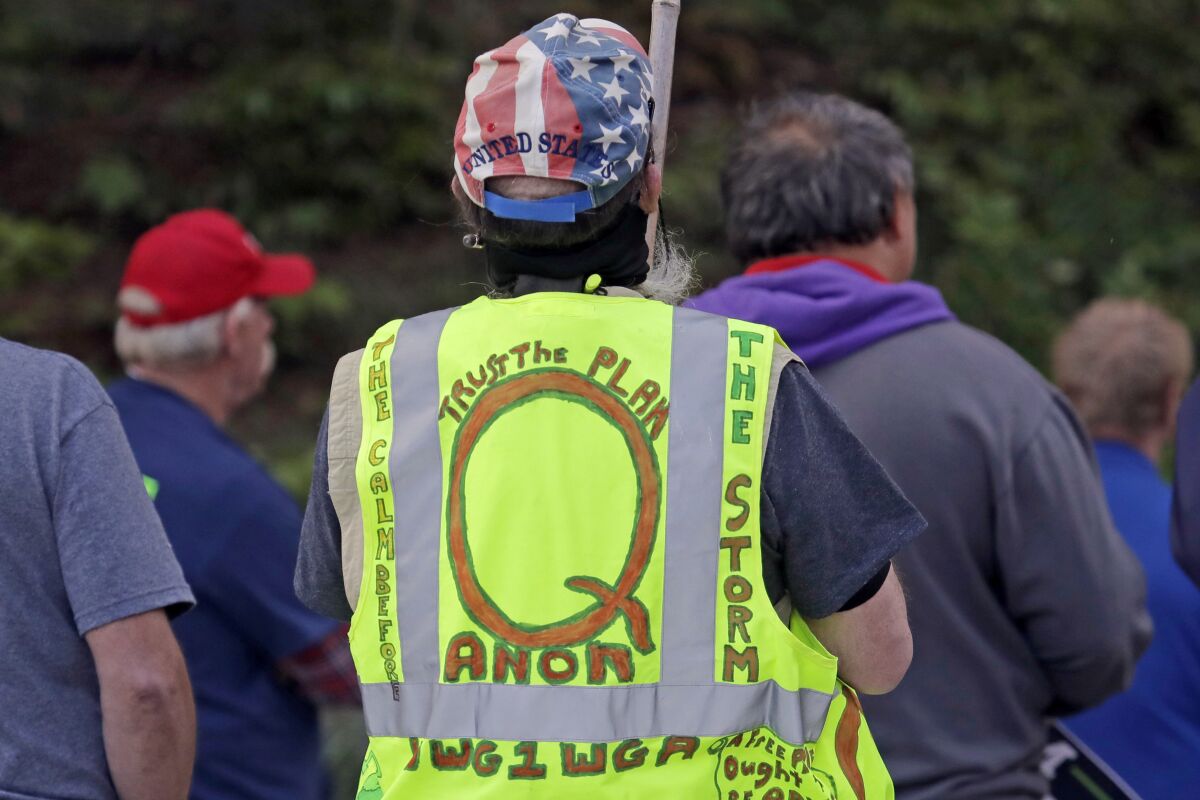 A person wears a vest promoting the QAnon conspiracy theory at a protest rally in Olympia, Wash., last May.