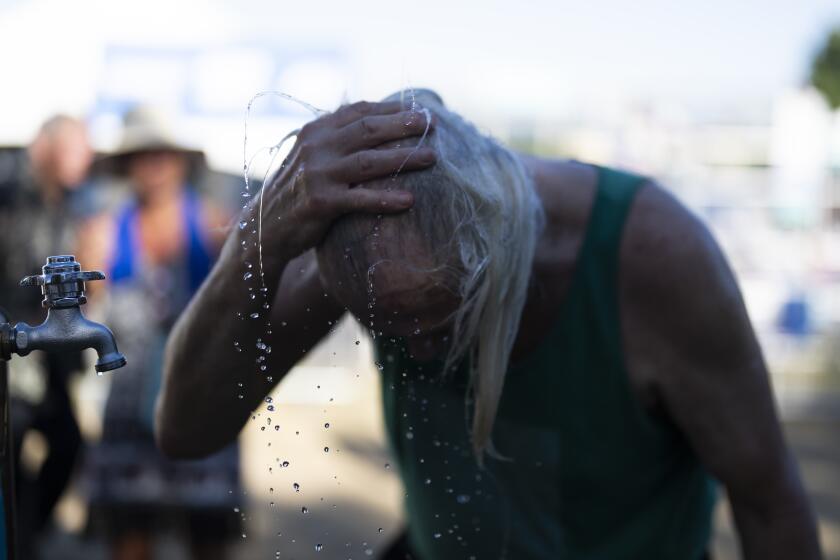 A person cools off during the Waterfront Blues Festival on Friday, July 5, 2024, in Portland, Ore. A slow-moving and potentially record-setting heat wave is spreading across the Western U.S., sending many residents in search of a cool haven from the dangerously high temperatures. (AP Photo/Jenny Kane)