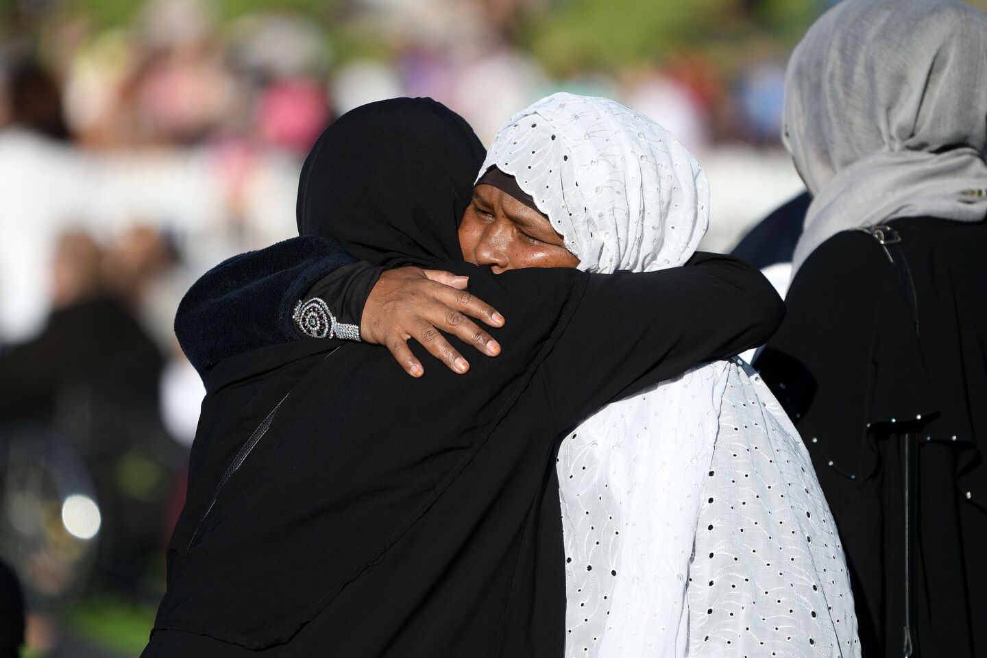 Mourners embrace at a vigil Sunday at the Basin Reserve in Wellington, New Zealand.