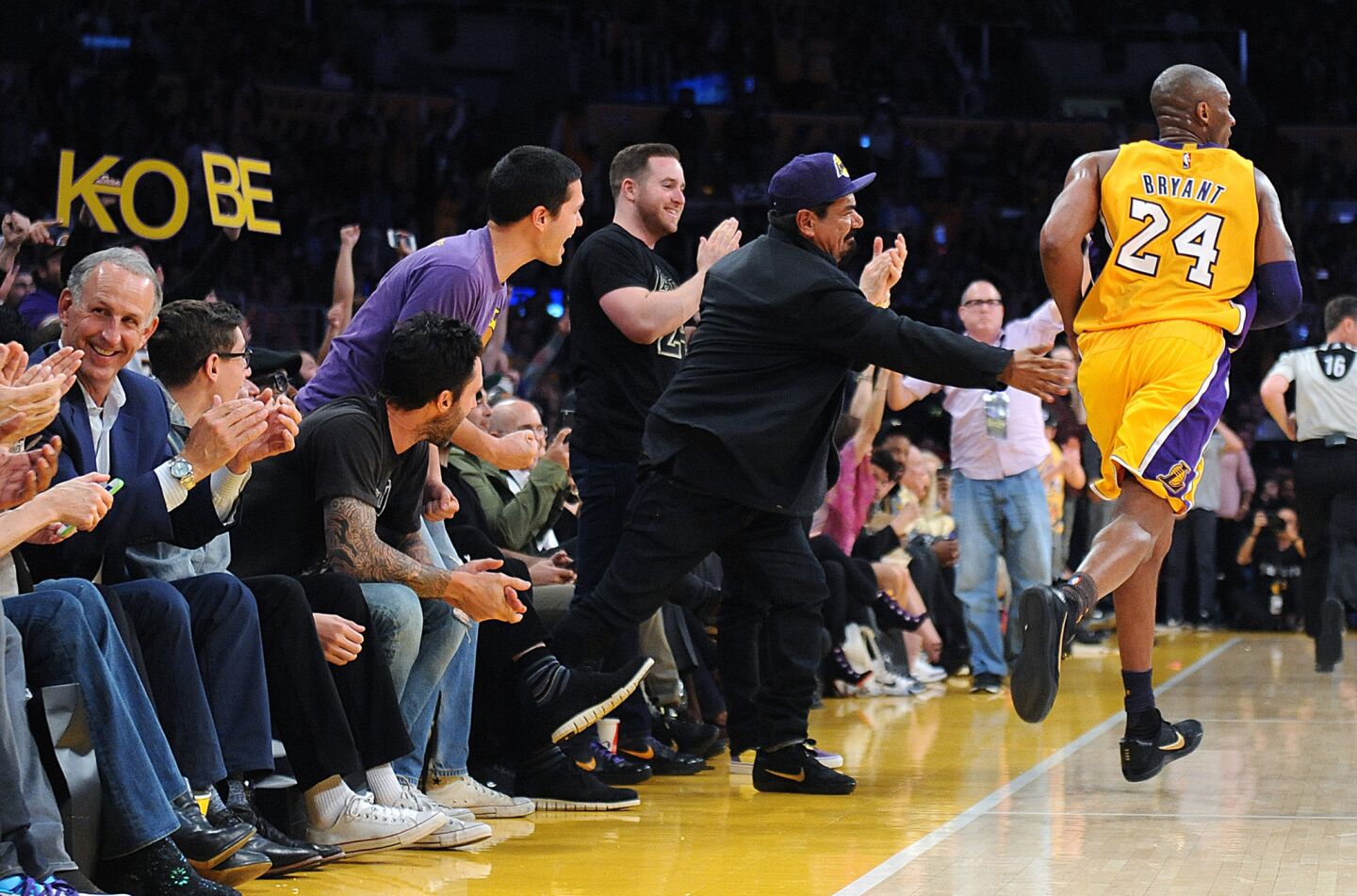 Kobe Bryant gets a slap from comedian George Lopez after making a three-pointer in his final game.