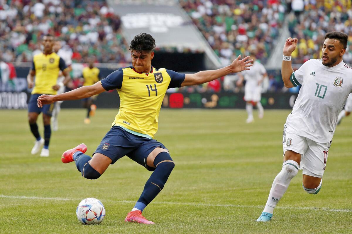 El defensor de Ecuador, Xavier Arreaga (14), aleja el balón frente al delantero de México, Alexis Vega.