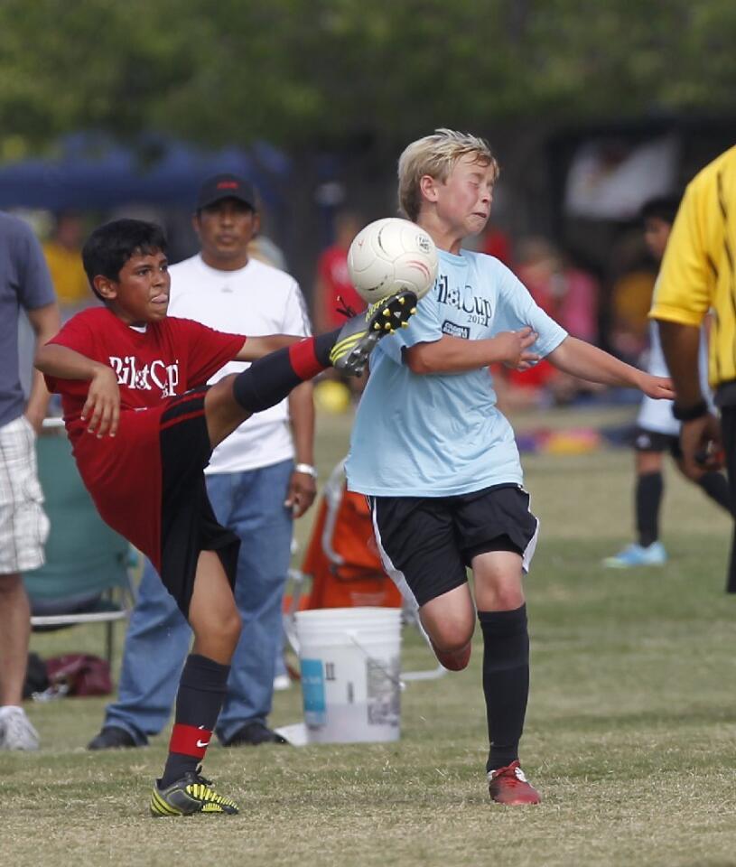 Wilson's Miguel Pena, left, boots the ball upfield narrowly missing a Newport Height's defender in the face during the boys' 5-6 gold division championship game in the Pilot Cup Sunday.