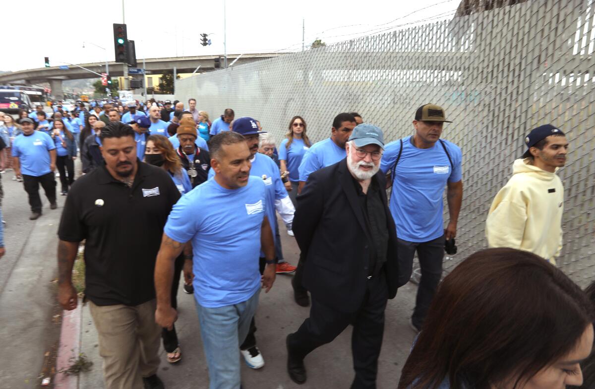 Father Greg Boyle, with glasses and a white beard, marches with program enrollees at Homeboy Industries to City Hall