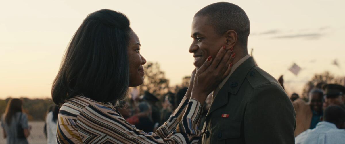 A woman cups the face of a man in military uniform in her hands.