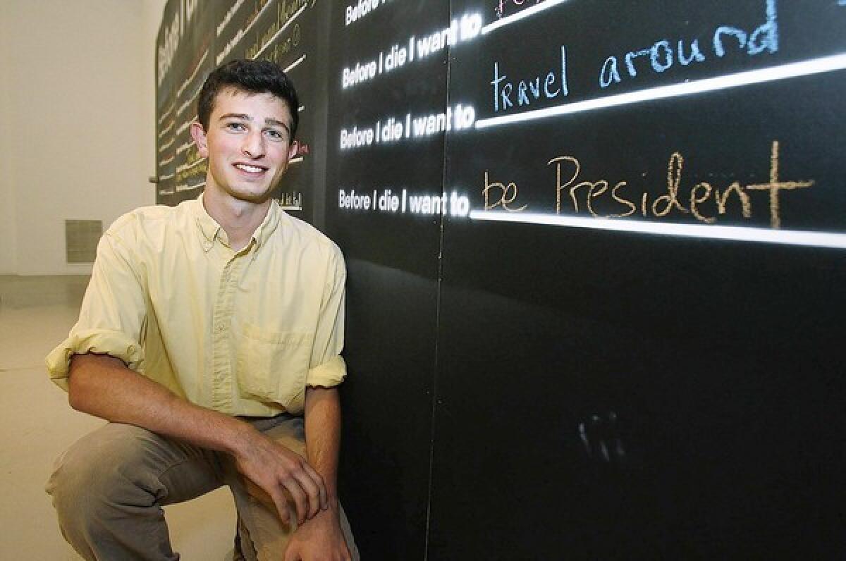 Kevork Kurdoghlian kneels next to his life wish to be president at the unveiling of a wall with the phrase "Before I die," where people can fill in the blank with their life wish in the fine arts gallery at Glendale Community College on Wednesday, July 10, 2013. The project was brought to GCC by 2nd year student Kevork Kurdoghlian who got the idea from a TED Talks video he saw online.