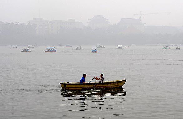 Two men row a boat as heavy smog shrouds Lake Beihai in Beijing. Pollution levels soared in the city a month before the start of the Olympic Games.