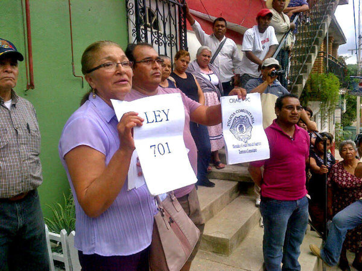 Marisela Jimenez, left, holds a copy of the law that allows indigenous pueblos to form community police squads. She is participating in a town meeting of Nestora Salgado's supporters in Olinala.