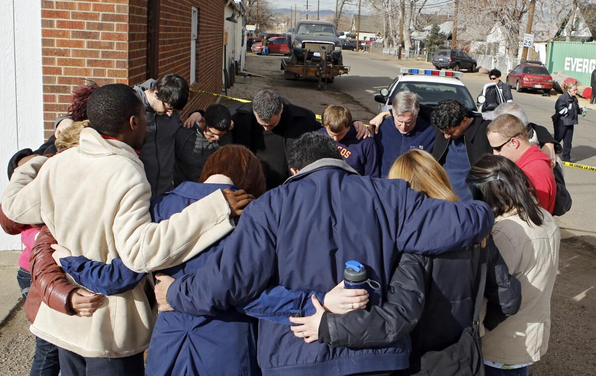 Members of a community church gather in a prayer circle a block from where a woman and two children were found dead and a third child wounded in Denver.