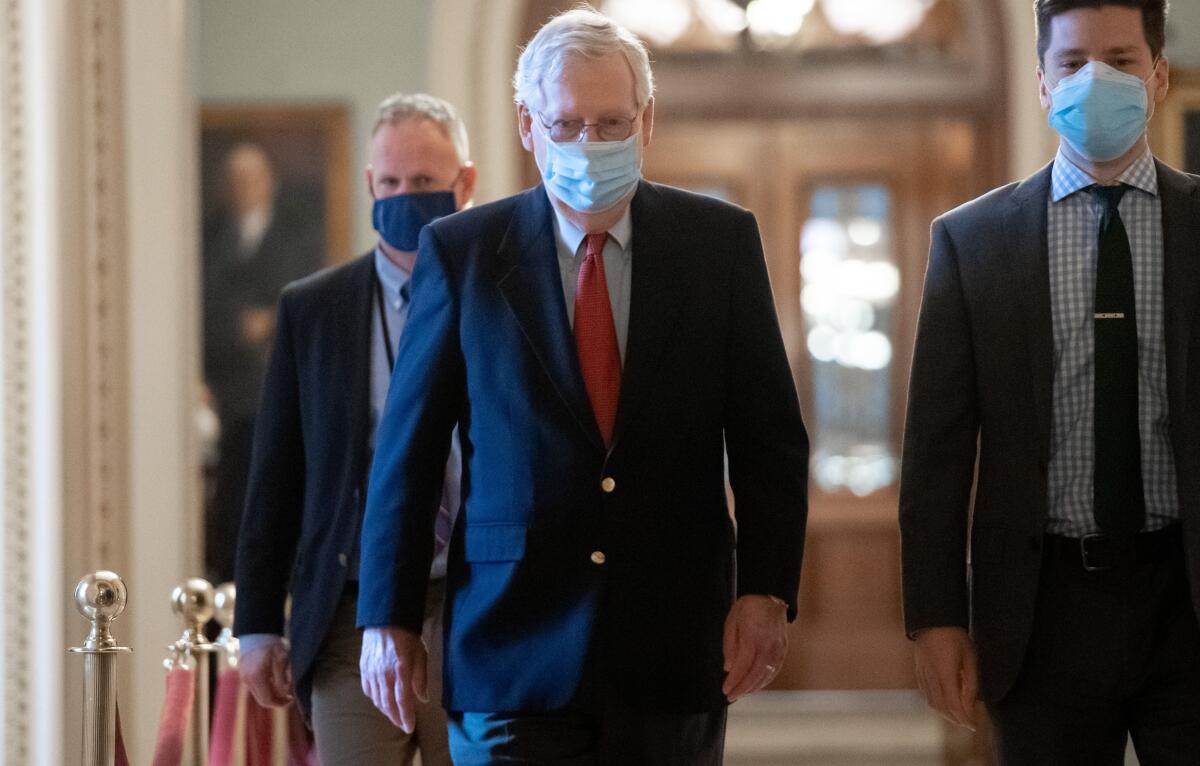 Rep. Mitch McConnell, wearing a mask along with two other men, walks to his office at the Capitol on Dec. 18.