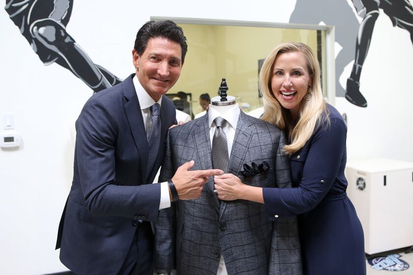 Clothier David Heil of David August, and Autumn Strier, co-founder and CEO of Miracles for Kids, dress a mannequin with one of the special ties that will benefit Strier's Tustin-based charity.