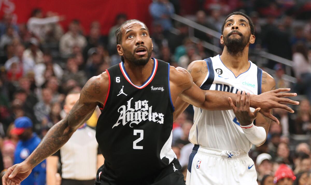 Clippers forward Kawhi Leonard, left, and Mavericks guard Kyrie Irving battle for rebounding position.