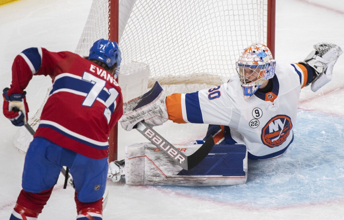 New York Islanders goaltender Ilya Sorokin, right, makes a stop against Montreal Canadiens' Jake Evans during third-period NHL hockey game action in Montreal, Friday, April 15, 2022. (Graham Hughes/The Canadian Press via AP)