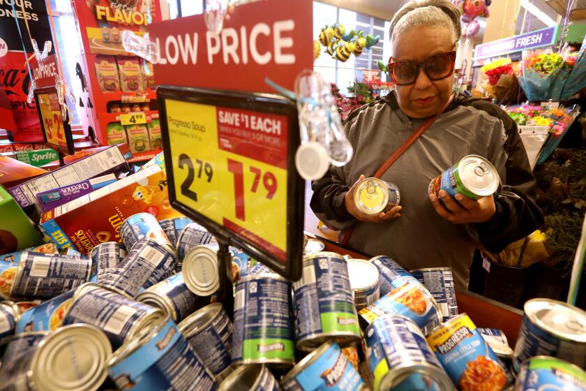 SHERMAN OAKS, CA - MARCH 7, 2024 - - Shardreata Moore, 67, looks over canned foods on sale while looking for bargains at Ralph's market in Sherman Oaks on March 7, 2024. Moore visits the Alicia Broadous-Duncan Multipurpose Senior Center in Sherman Oaks during the week where she can get a free meal. "It's tough over the weekend," Moore said about getting something to eat when the senior center is closed. She buys a foot long sandwich from Subway from time to time. She cuts it up in three pieces and says she's able to get three meals out of it. (Genaro Molina/Los Angeles Times)
