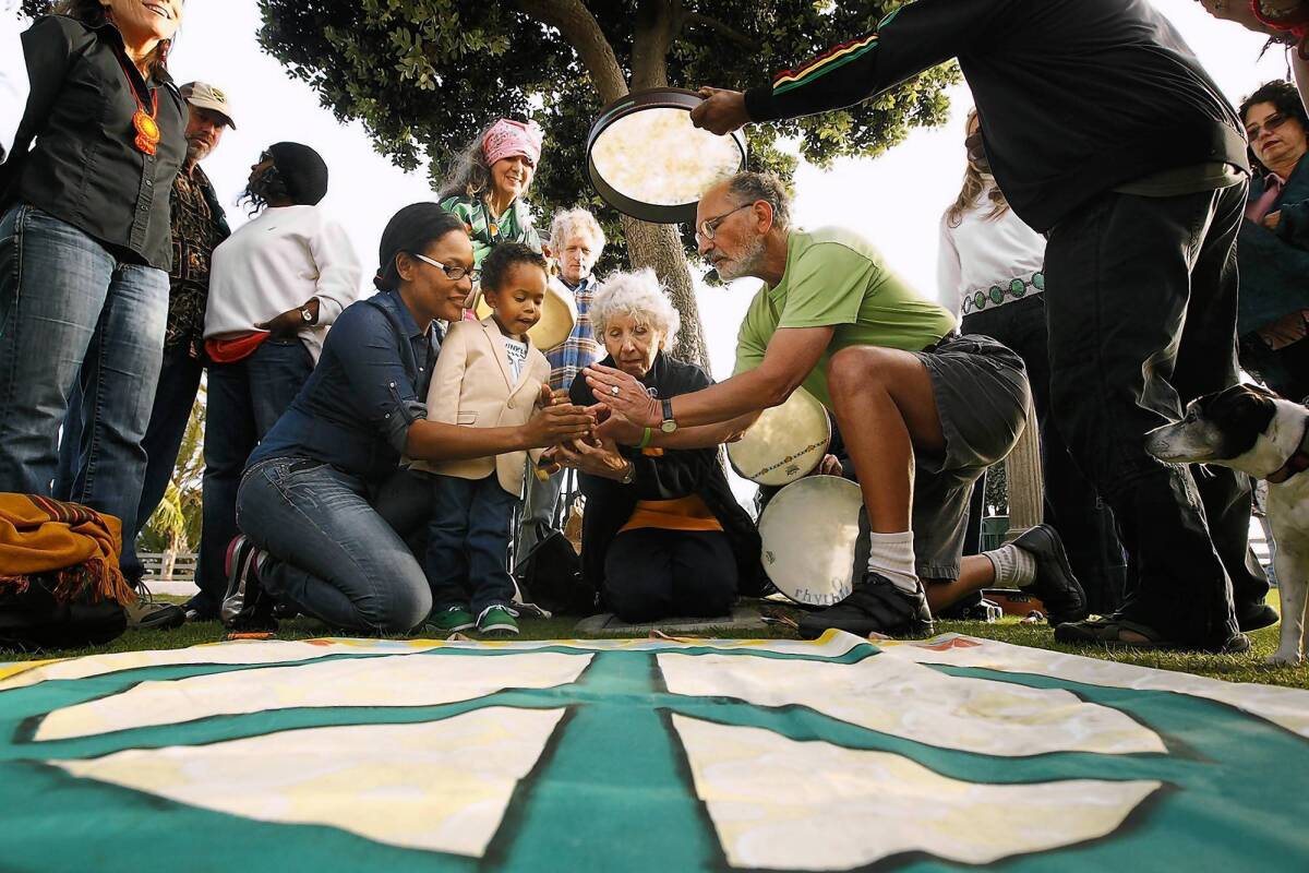 Activist Jerry Rubin, right, with his wife Marissa, along with Shay White, left, and her son Elias Washington, light a candle during a ceremony at the Children's Tree of Life at Santa Monica's Palisades Park in honor of Earth Day.