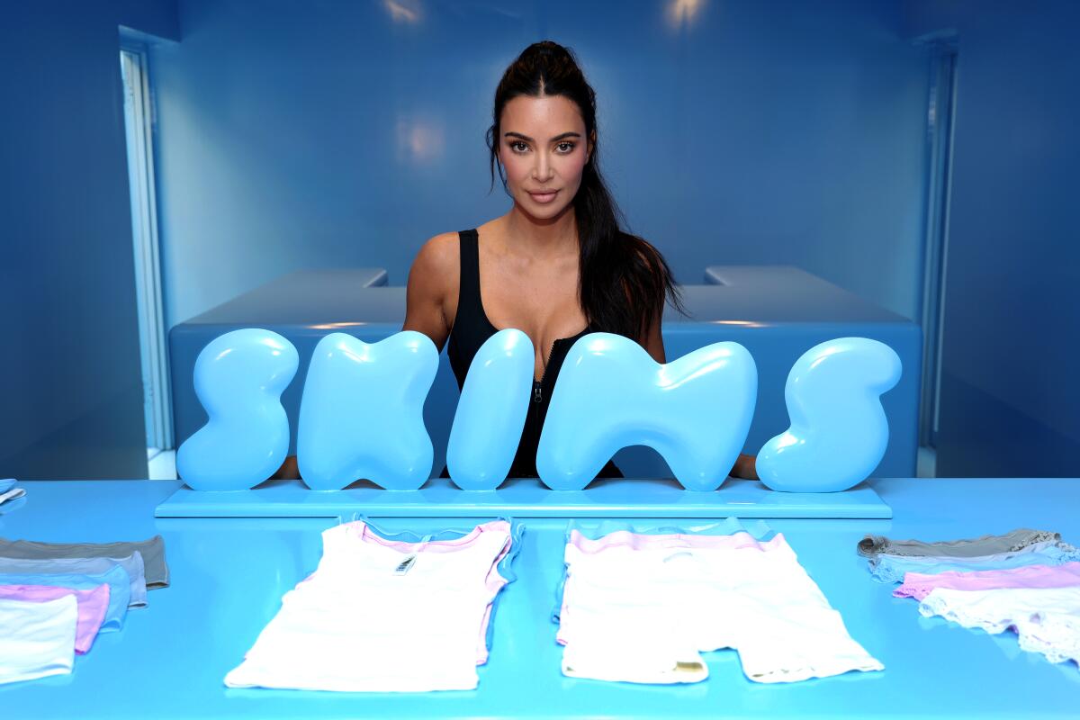 Kim Kardashian stands behind the Skims logo.