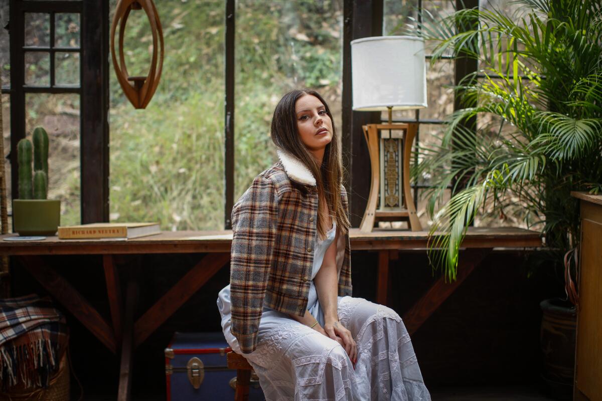 A woman in a flannel coat sits for a photo portrait