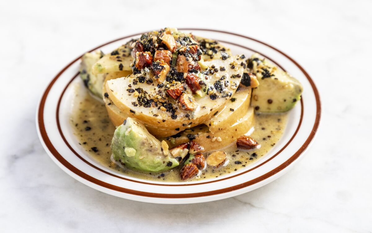 A plate holds a salad of dressed avocado and Asian pear.
