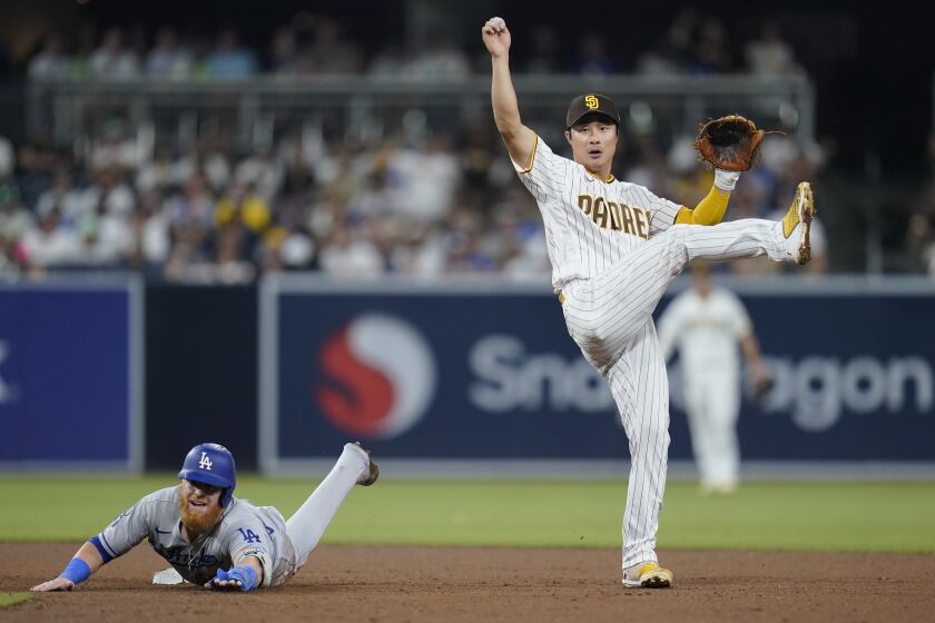 San Diego Padres shortstop Ha-Seong Kim, right, watches his throw to first too late for the double play as Los Angeles Dodgers' Justin Turner slides after being forced during the sixth inning of a baseball game Tuesday, Sept. 27, 2022, in San Diego. Max Muncy was safe at first and Trea Turner scored. (AP Photo/Gregory Bull)