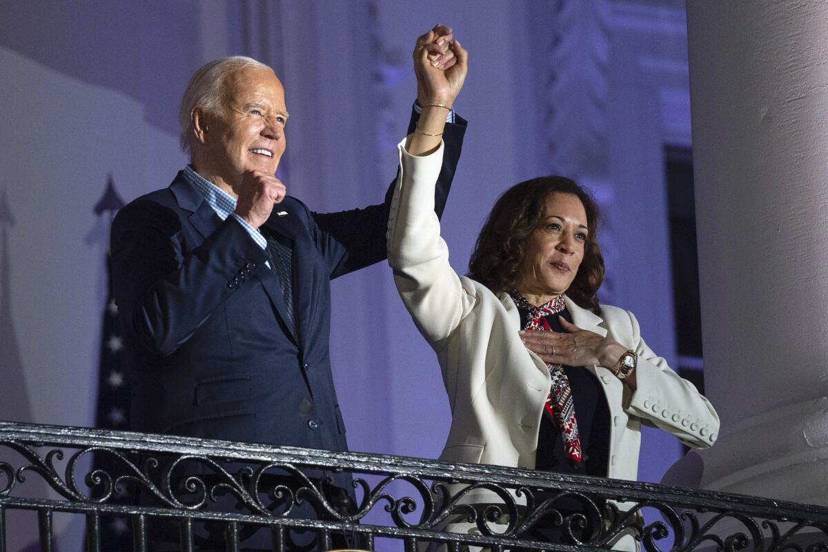 President Biden and Vice President Kamala Harris raise joined hands on a White House balcony.