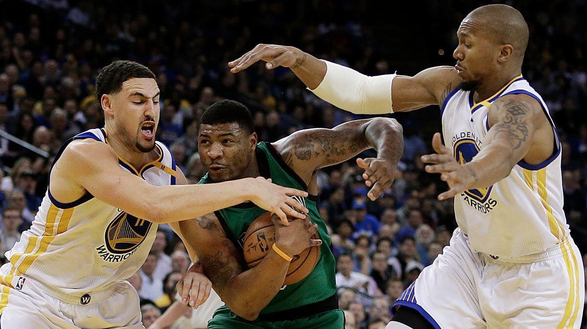 Celtics guard Marcus Smart tries to drive between Warriors guard Klay Thompson, left, and forward David West during the second half of a game earlier this week.