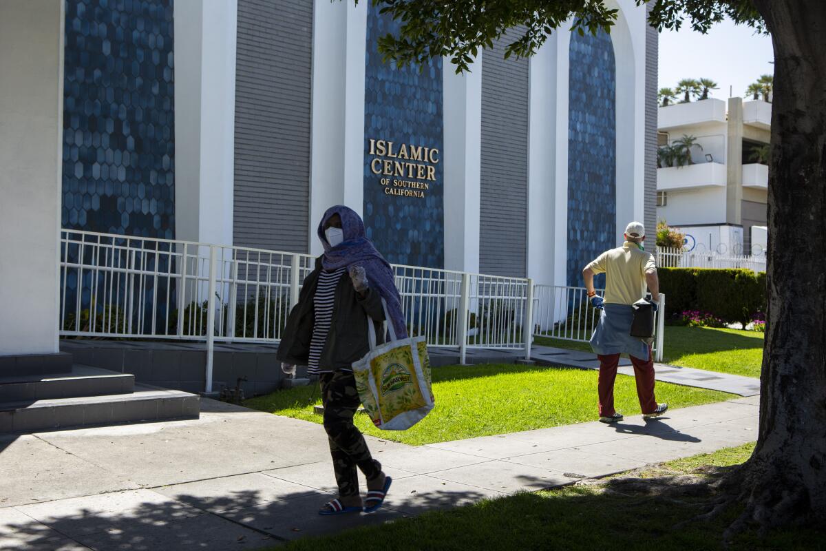 Pedestrians stroll by the Islamic Center of Southern California. Mosques may have to cut back further if they receive fewer donations while coronavirus orders keep the faithful at home during Ramadan, typically a big fundraising time.
