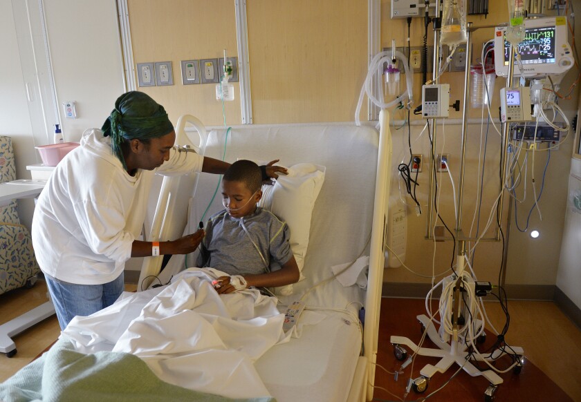 Melissa Lewis of Denver helps her son, Jayden Broadway, 9, at Children's Hospital Colorado in Aurora. He was treated for enterovirus D-68 and released.