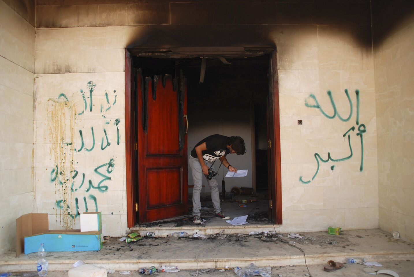 A man looks at documents at the U.S. Consulate in Benghazi, Libya, after an attack that killed four Americans, including U.S. Ambassador J. Christopher Stevens. The graffiti reads "no God but God," "God is great" and "Muhammad is the Prophet."