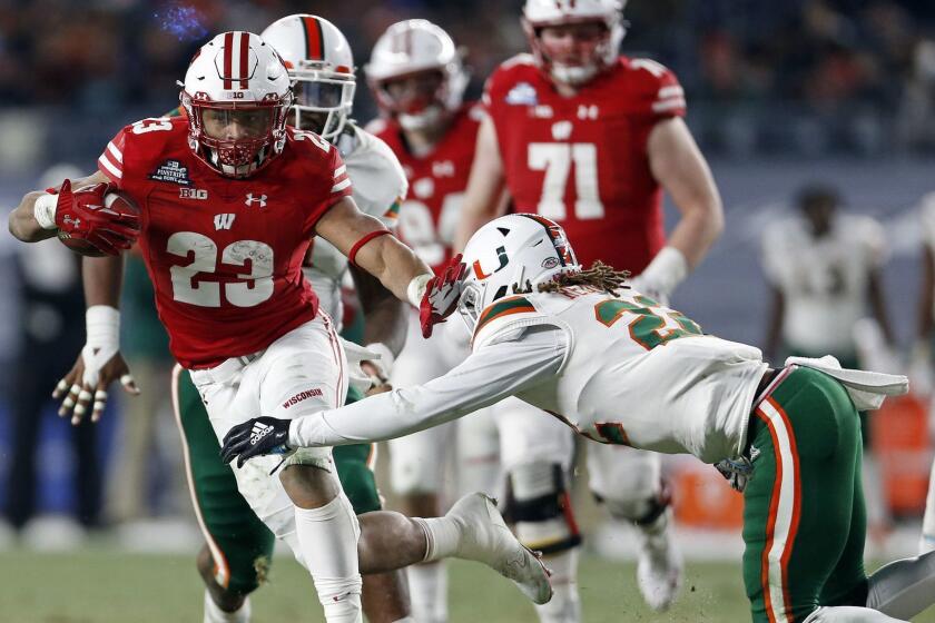 Wisconsin running back Jonathan Taylor (23) breaks a tackle attempt by Miami defensive back Sheldrick Redwine (22) during the first half of the Pinstripe Bowl NCAA college football game Thursday, Dec. 27, 2018, in New York. (AP Photo/Adam Hunger)