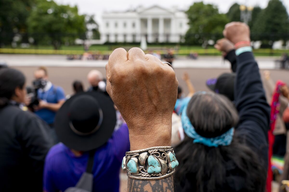 FILE - Wolf Ramerez of Houston, Texas, center, joins others with the Carrizo Comecrudo Tribe of Texas in holding up his fists as indigenous and environmental activists protest in front of the White House in Washington, Oct. 11, 2021. President Joe Biden will announce steps Monday, Nov. 15, to improve public safety and justice for Native Americans during the first tribal nations summit since 2016, the White House said. (AP Photo/Andrew Harnik, File)