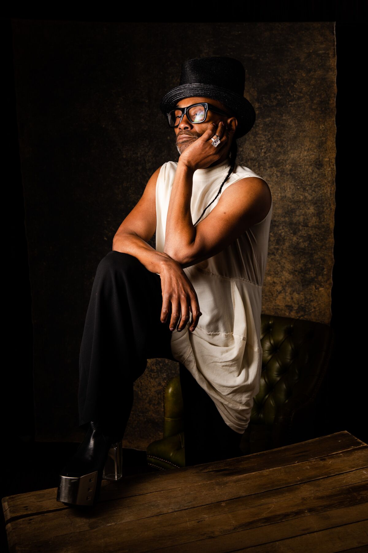 Billy Porter places one hand on his chin and the other on his knee while posing at the Festival of Books photo studio 