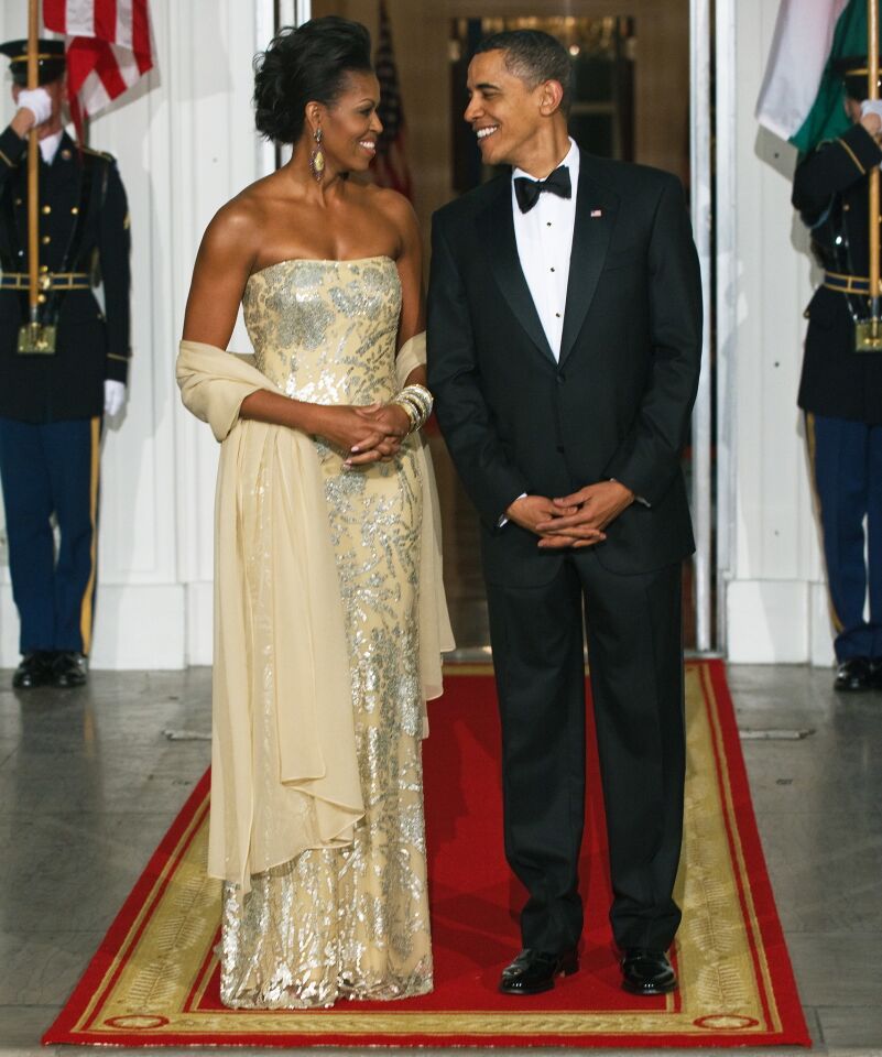 For the first state dinner of the Obama administration, honoring Indian Prime Minister Manmohan Singh and his wife Gursharan Kaur, the first lady wore a Champagne-colored strapless gown gleaming with silver floral appliqué by Mumbai-born, New York based, Indian American designer Naeem Khan.