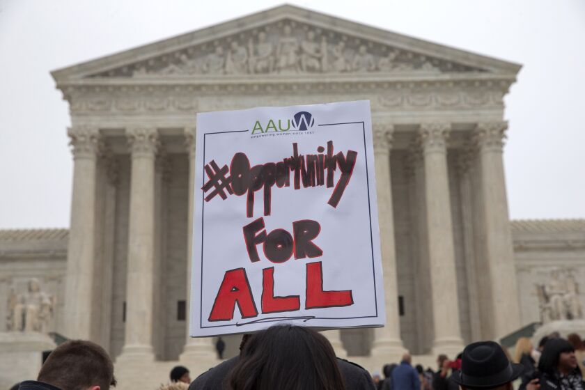 Pamela Yuen, with the American Association of University Women, holds a sign in favor of affirmative action outside of the Supreme Court in Washington, Wednesday, Dec. 9, 2015, as the court hears oral arguments in the Fisher v. University of Texas at Austin affirmative action case. (AP Photo/Jacquelyn Martin)