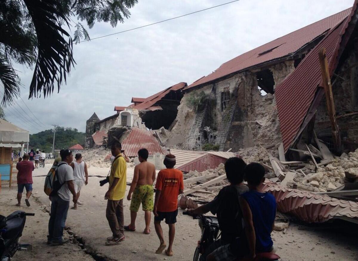 People walk past the damaged Church of San Pedro in the town Loboc, on Bohol island after a 7.2 magnitude earthquake struck the region Tuesday morning.