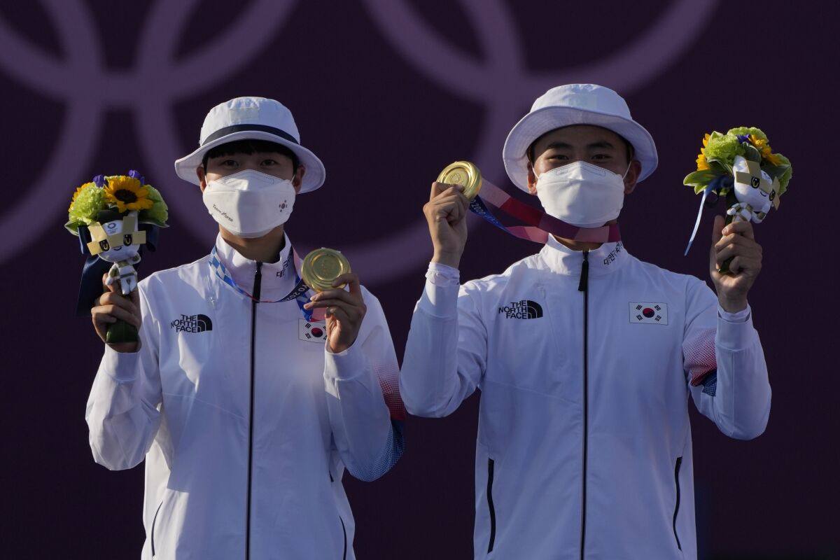 South Korea's An San, left, and Je Deok Kim hold up medals and bunches of flowers
