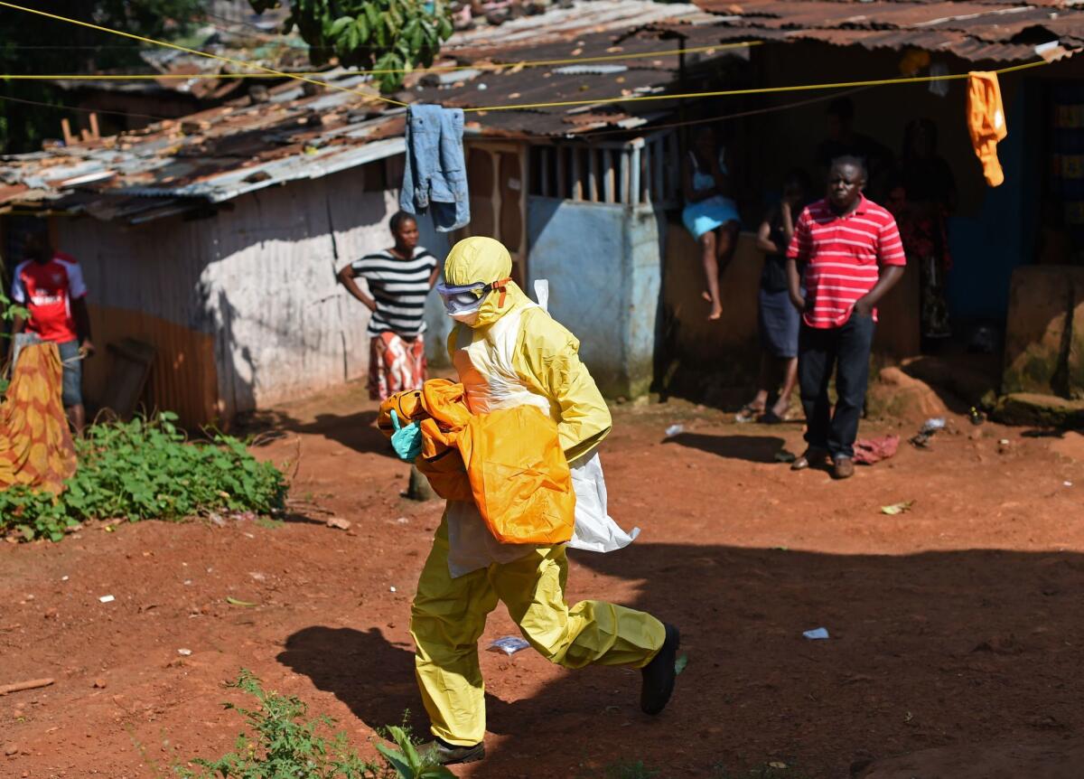 A member of a Red Cross burial team carries the body of a child believed to have died of Ebola in the Sierra Leone capital, Freetown, in November.