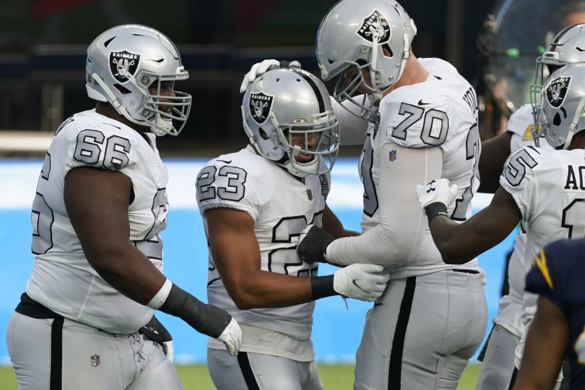 Las Vegas Raiders running back Devontae Booker (23) reacts with teammates offensive tackle Sam Young (70) and offensive guard Gabe Jackson (66) after scoring a touchdown during the first half of an NFL football game against the Los Angeles Chargers, Sunday, Nov. 8, 2020, in Inglewood, Calif. (AP Photo/Ashley Landis)